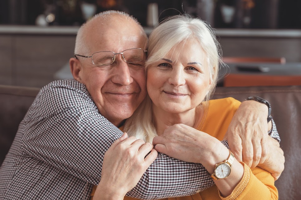 Pareja de adultos mayores abrazados sonriendo con calidez